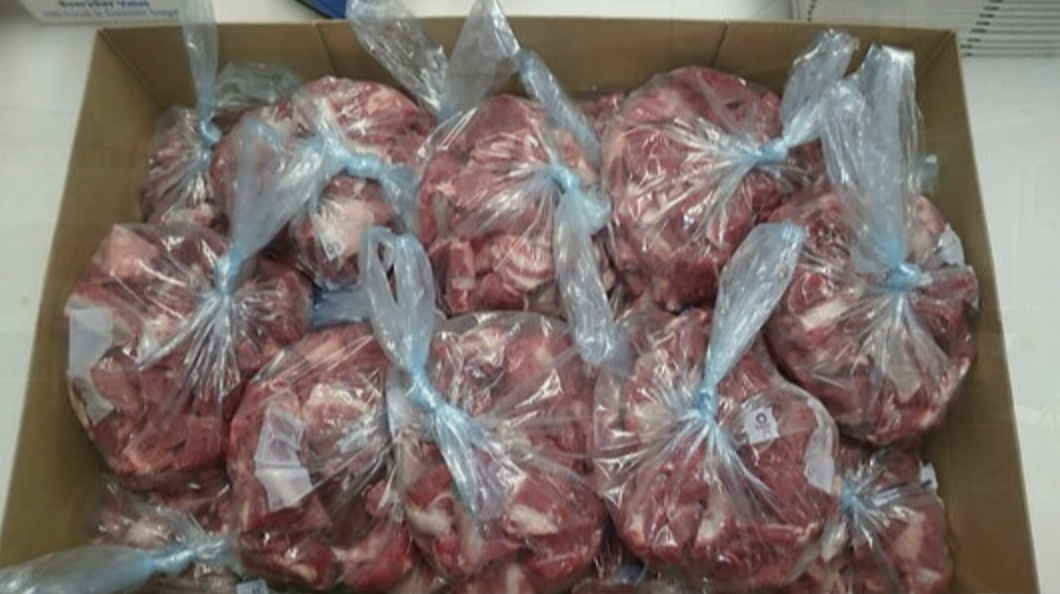 A box filled with lots of transparent plastic bags containing raw meat.